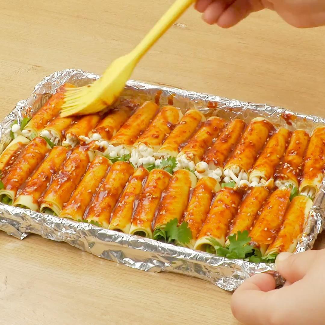 一张锡纸,先刷一层植物油,再刷一层酱汁,然后把卷好的豆皮卷铺在上面